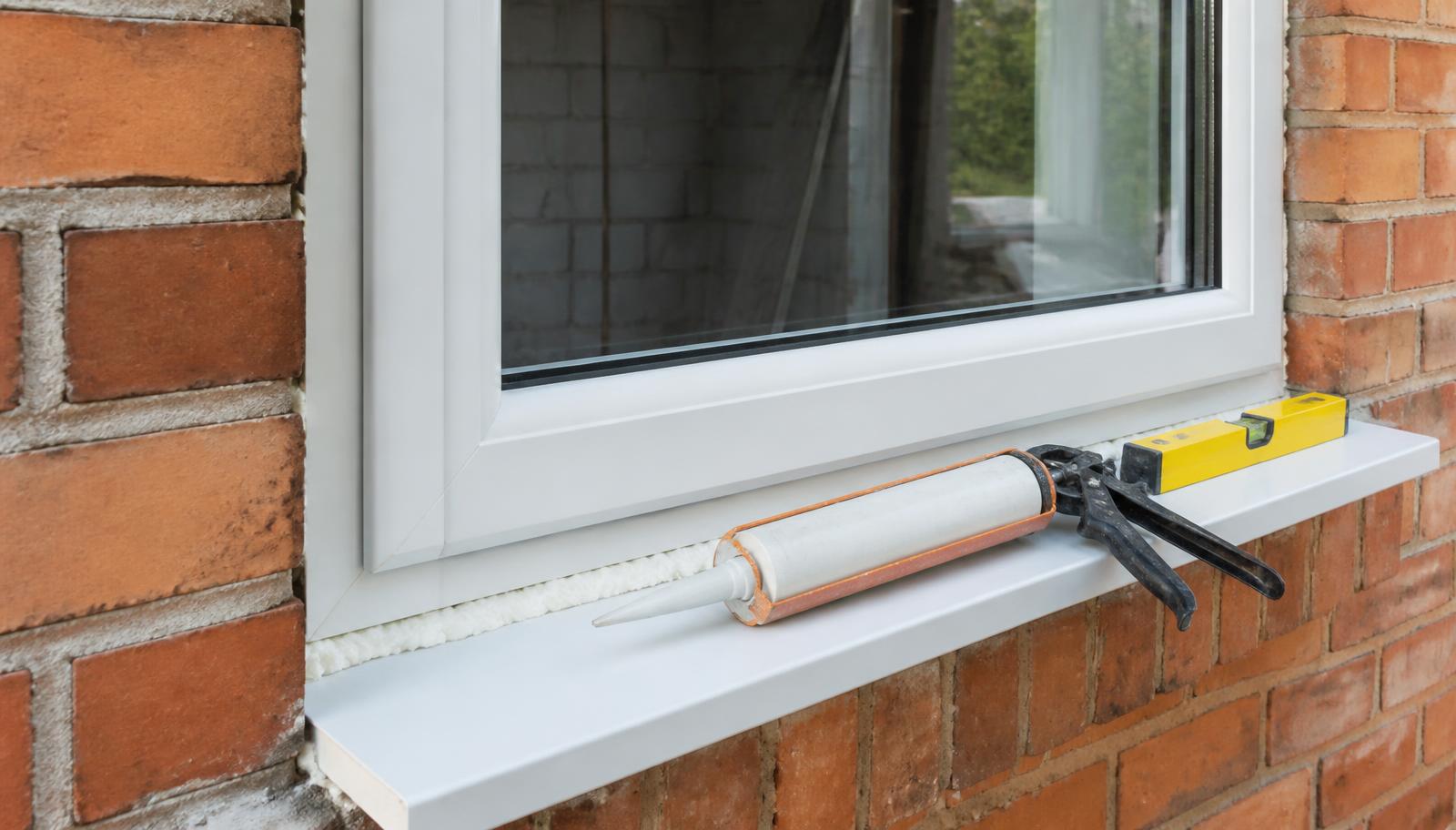 Newly installed window frame being sealed and levelled into a brick opening during a FENSA-certified installation